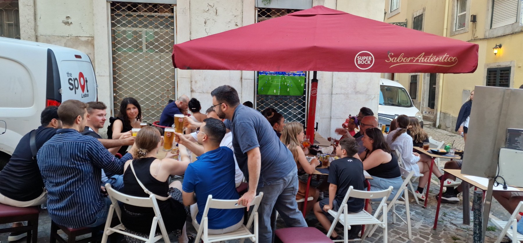 Guests enjoying outdoor seating under a red umbrella at The Spot Lisboa