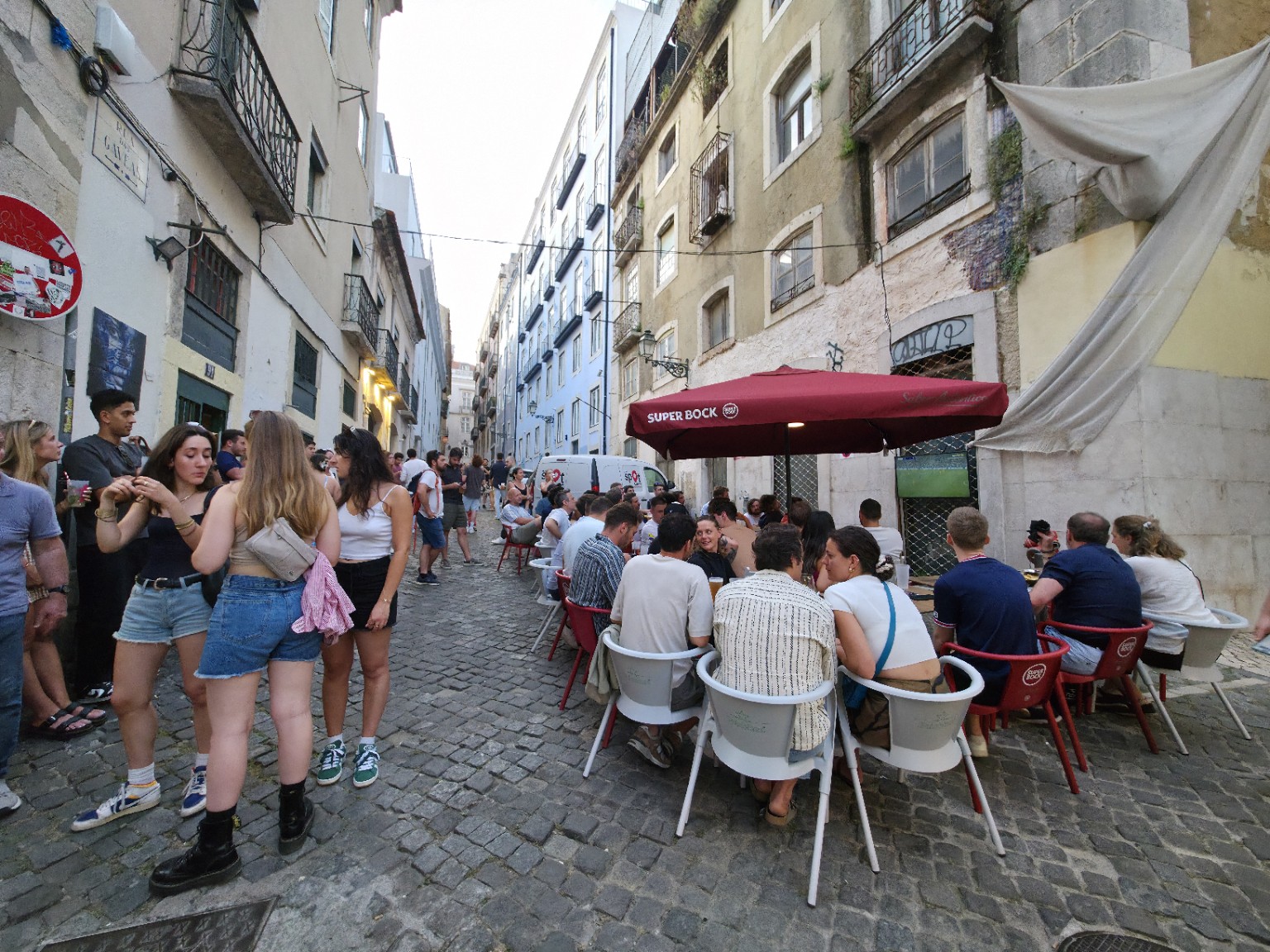 A lively gathering around outdoor tables beneath the red umbrella